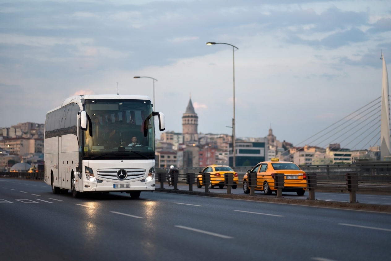 White group coach driving in Istanbul with Galata Tower in the background.